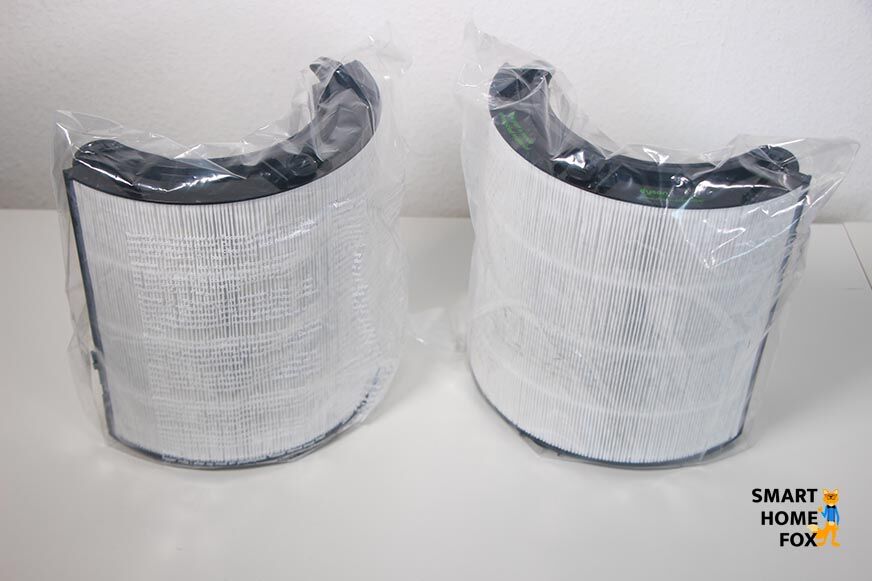 Die Filtereinheiten vom Dyson Purifier Cool sind in Schutzfolie verpackt und stehen auf einem Tisch.